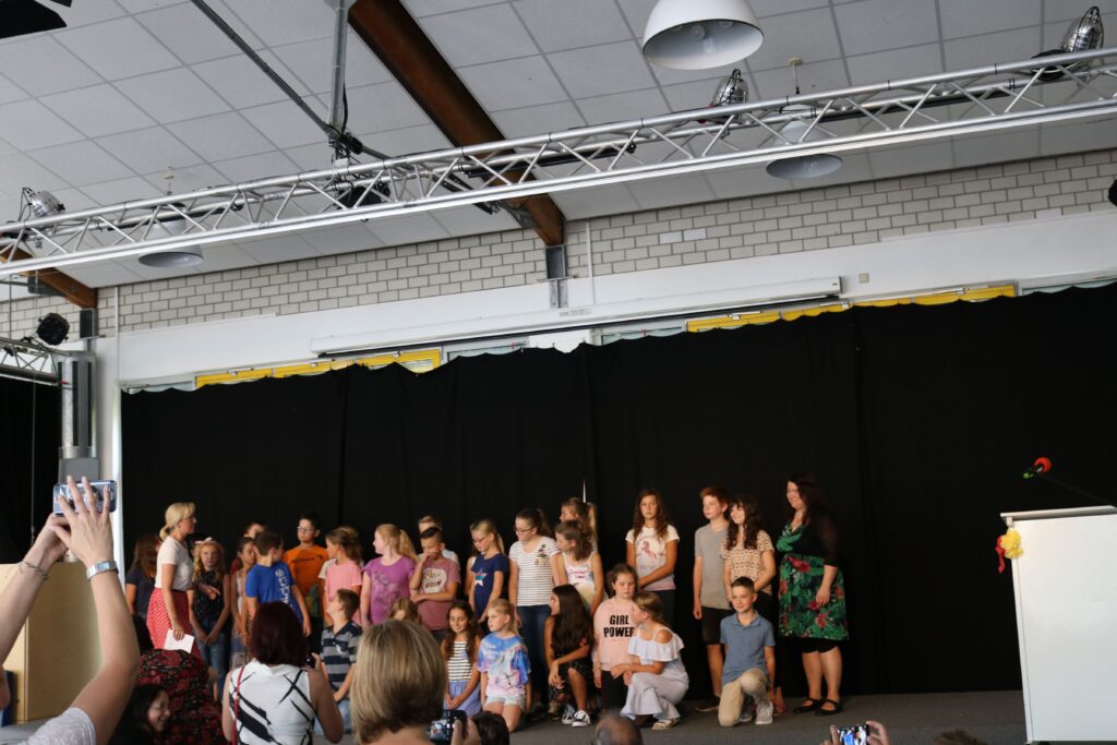Gruppe von Schülern und Lehrern auf einer Bühne bei einer Veranstaltung.