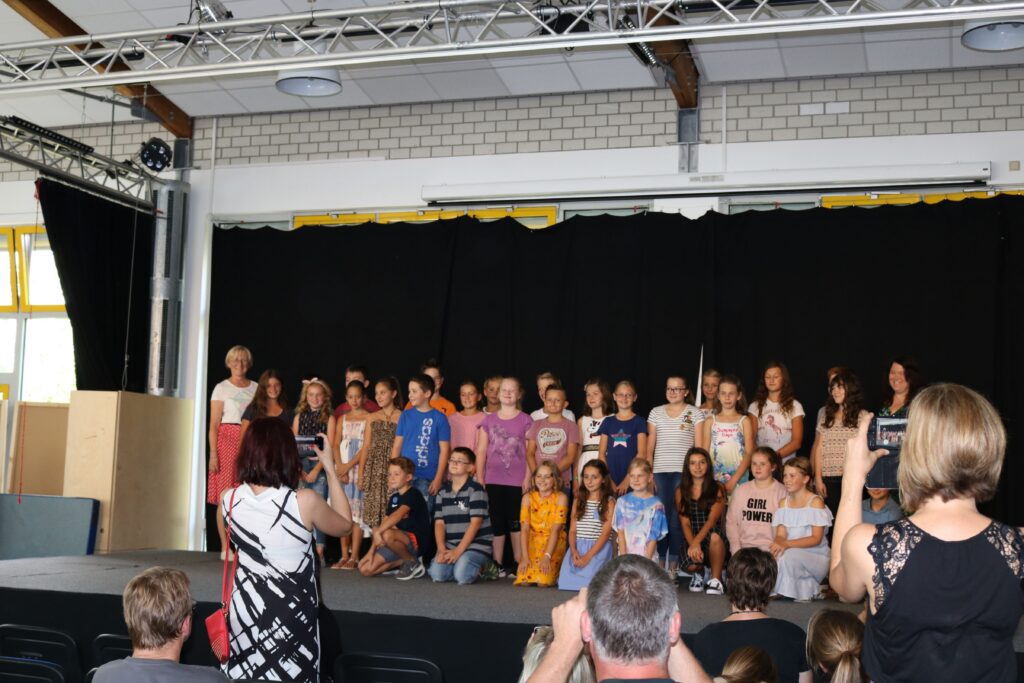 Schüler stehen in Gruppen auf der Bühne bei einer Veranstaltung.
