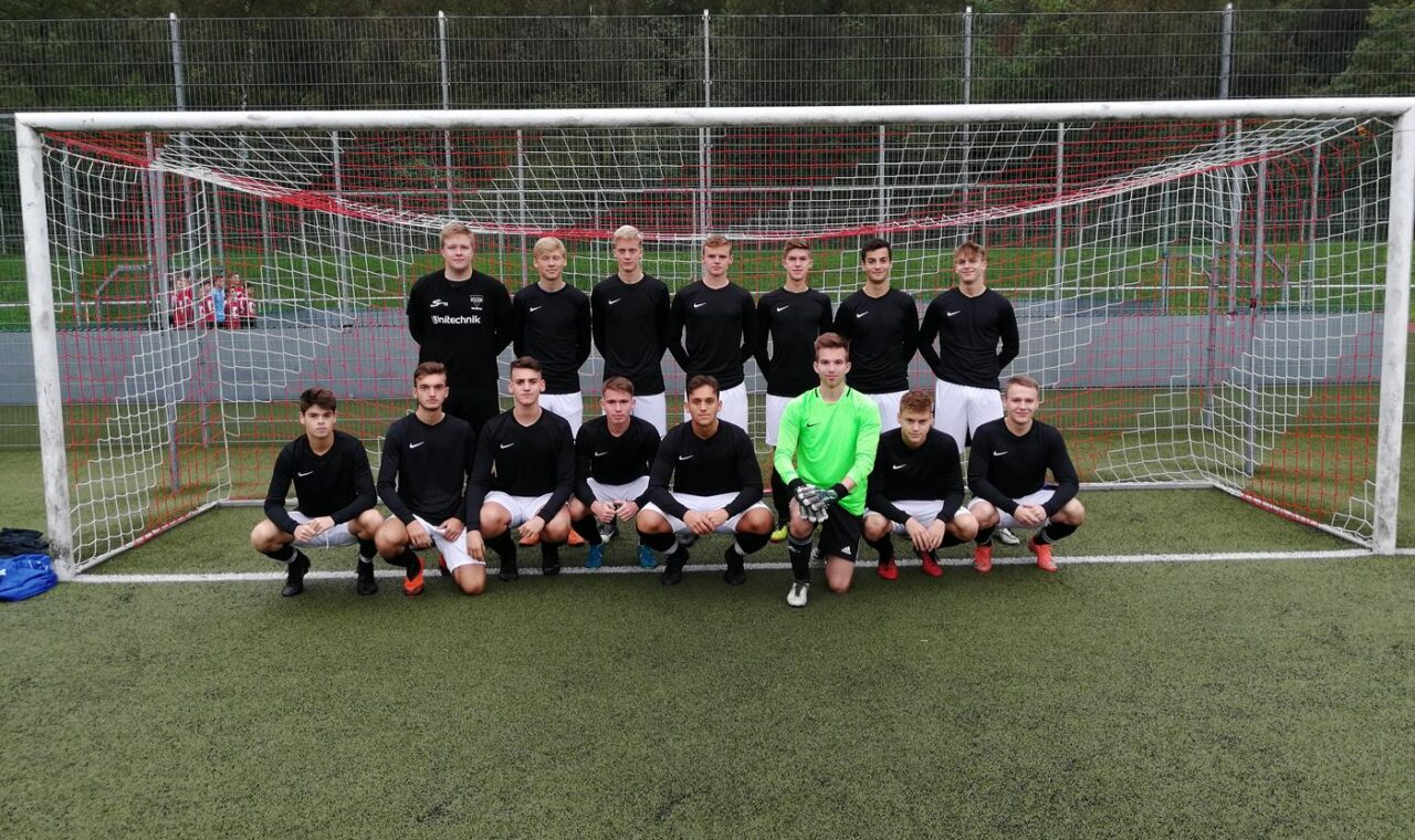 Mannschaftsfoto einer Fußballmannschaft vor dem Tor. 18 Spieler in einheitlicher Kleidung.