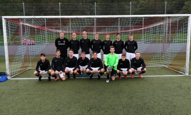Mannschaftsfoto einer Fußballmannschaft vor dem Tor. 18 Spieler in einheitlicher Kleidung.