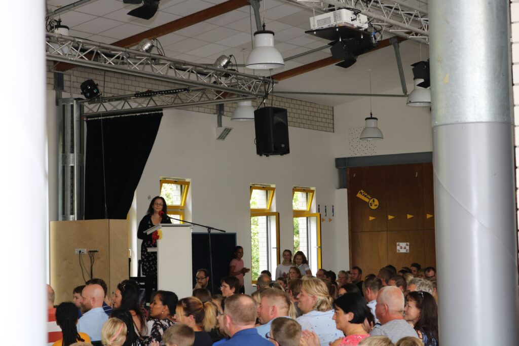Veranstaltung mit Rednerin vor Publikum in einem Saal.