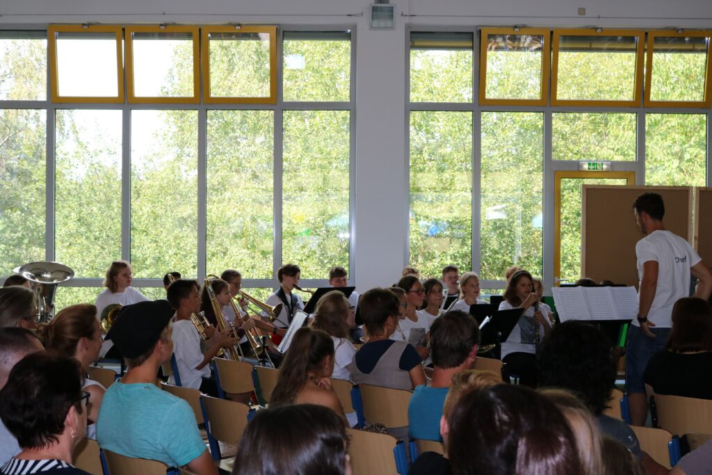Schüler spielen im Schulgebäude Musik vor einem Publikum.