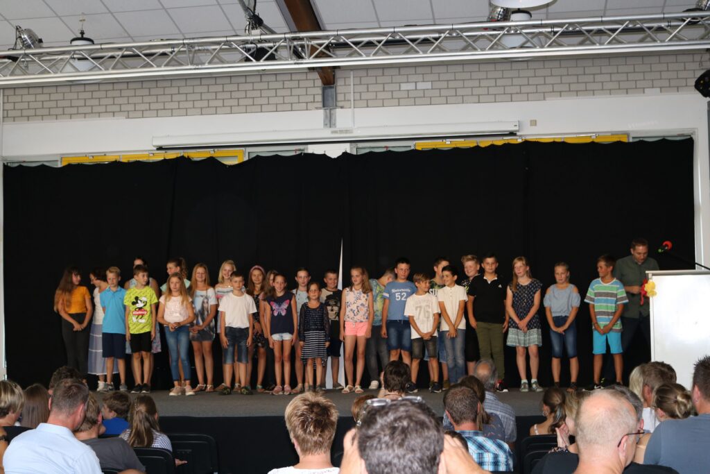 Schüler stehen auf der Bühne während einer Aufführung oder Veranstaltung.