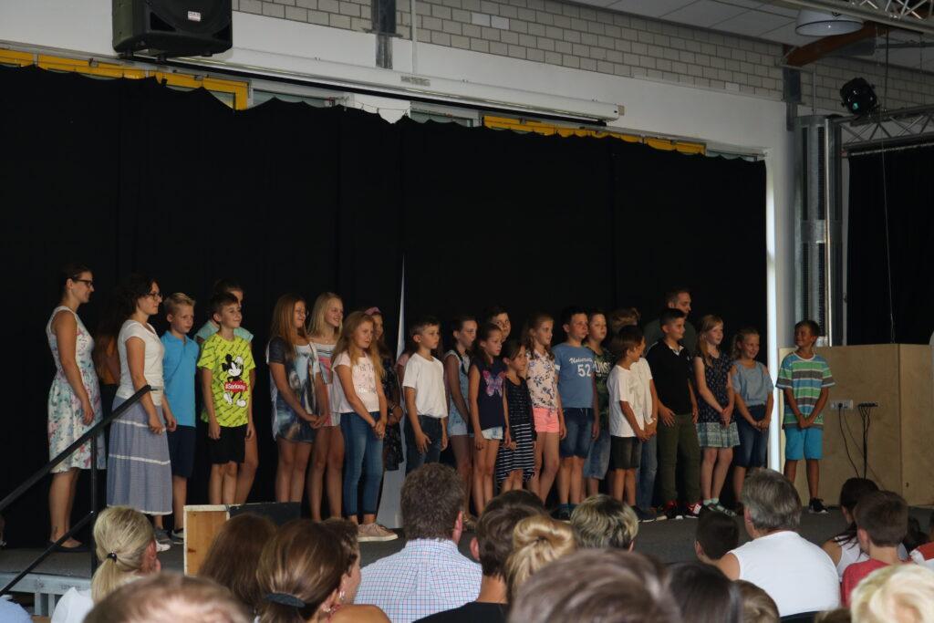 Schüler stehen auf der Bühne und singen vor Publikum.
