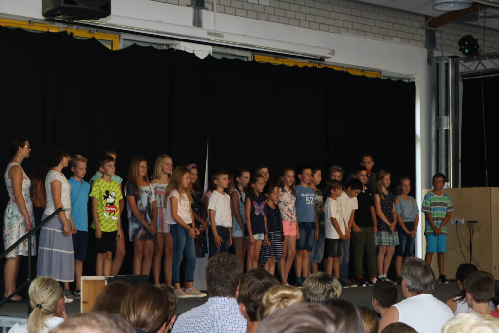 Schüler stehen auf einer Bühne und singen vor Publikum.