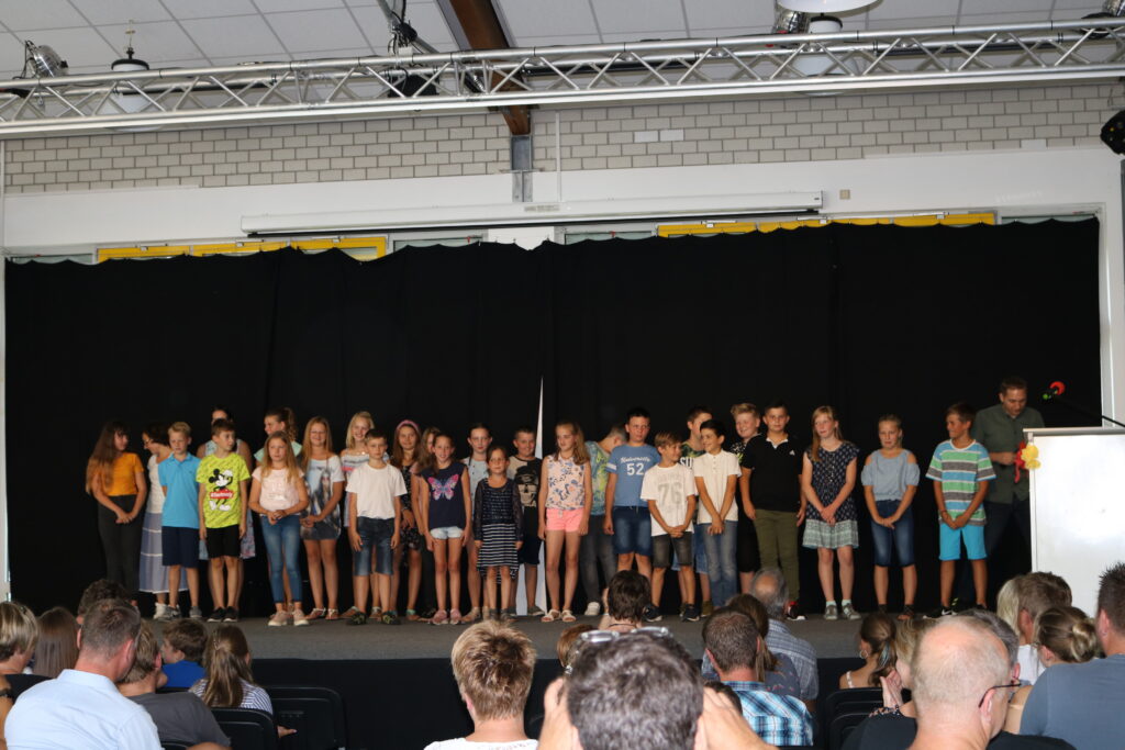 Schüler stehen auf der Bühne während einer Veranstaltung vor Publikum.