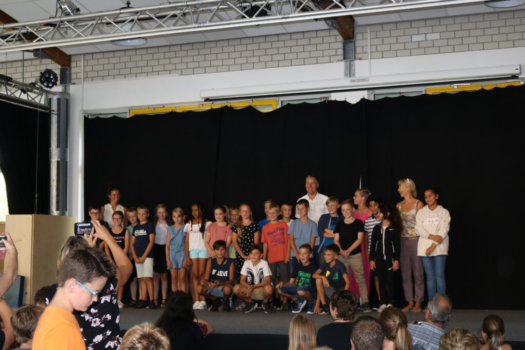 Schüler stehen auf einer Bühne, umgeben von Zuschauern.