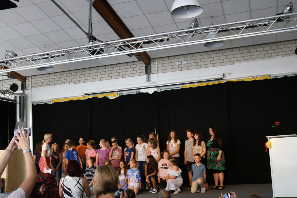 Gruppe von Schülerinnen und Schülern auf einer Bühne bei einer Veranstaltung.