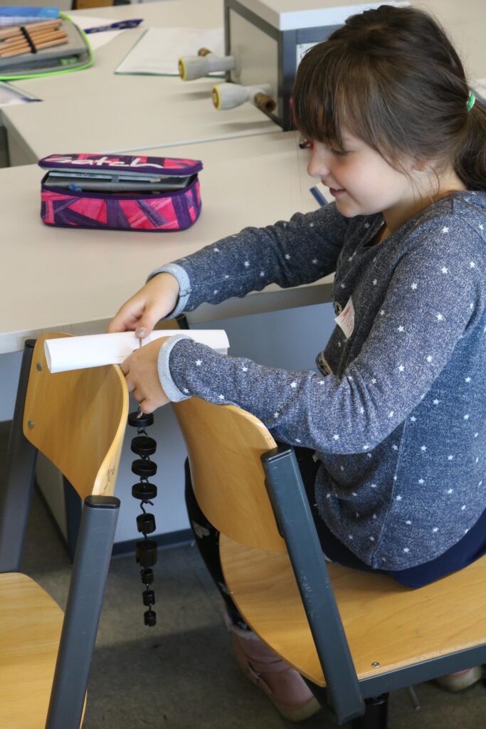 Ein Mädchen sitzt in einem Klassenraum und arbeitet an einem Projekt.