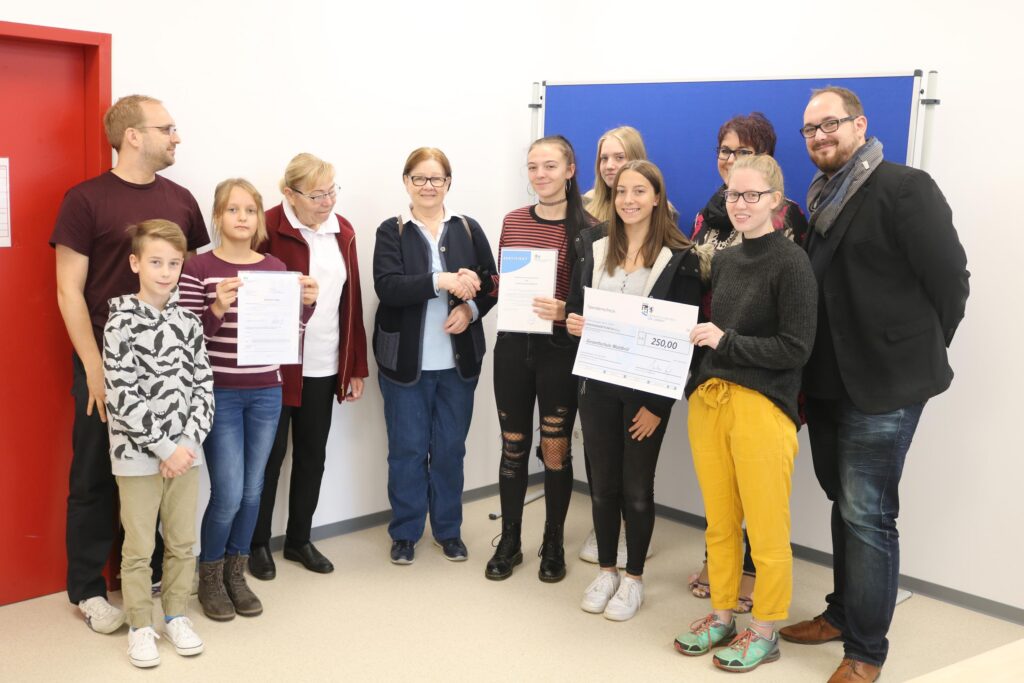 Gruppe von Schülerinnen, Lehrern und Eltern bei einer Auszeichnung.