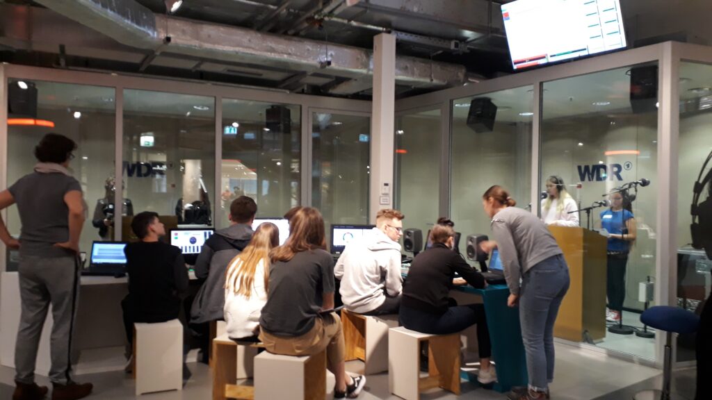 Schüler sitzen im WDR-Studio und arbeiten an Computerarbeitsplätzen.
