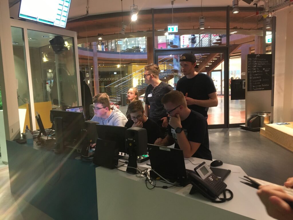 Studierende arbeiten an Computerstationen in einem modernen Studio.