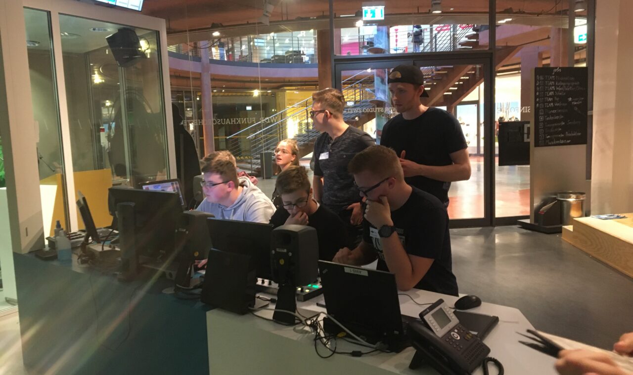 Studierende arbeiten an Computerstationen in einem modernen Studio.