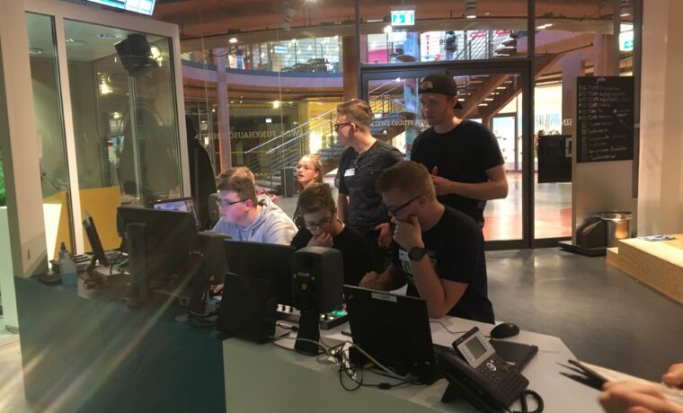 Studierende arbeiten an Computerstationen in einem modernen Studio.