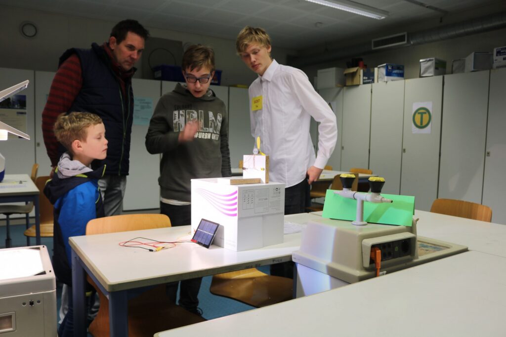 Schüler präsentieren ein Projekt an einem Tisch im Klassenzimmer.