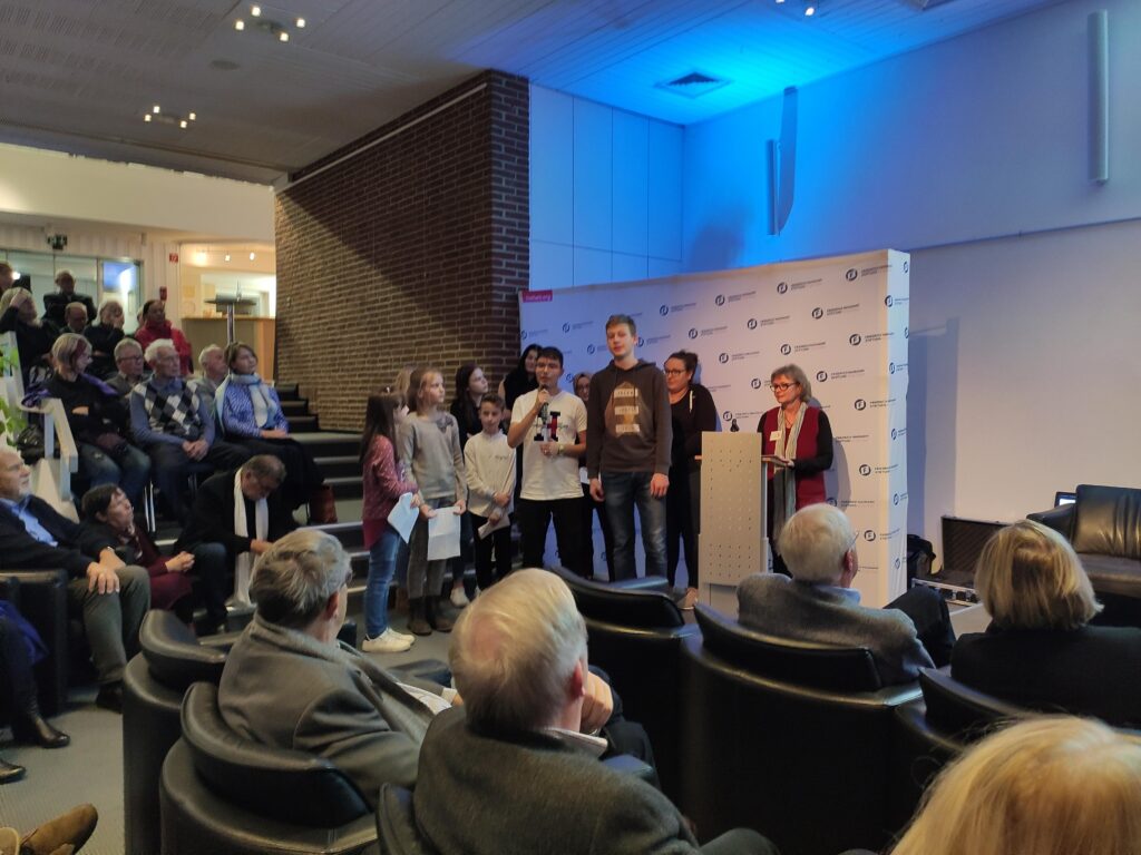 Veranstaltung mit Rednerinnen und Publikum, Jugendliche stehen an einem Podium.
