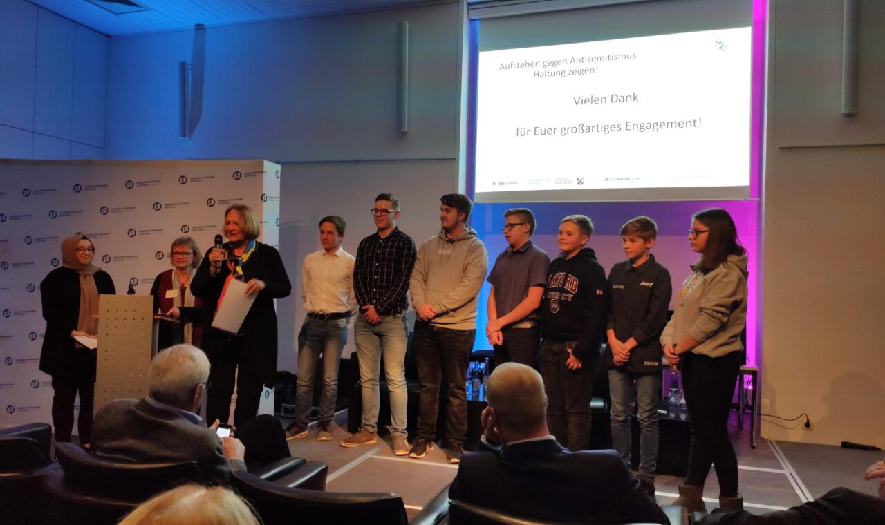 Schülergruppe steht auf der Bühne bei einer Veranstaltung.