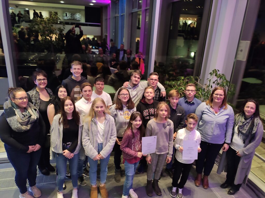 Gruppe von Schülern und Lehrern pose für ein Foto in einem Veranstaltungsraum.