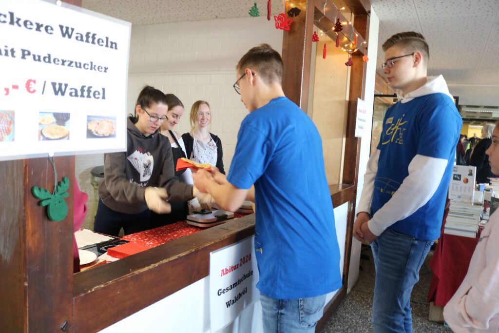 Schüler verkaufen Waffeln an einem Stand während einer Veranstaltung.