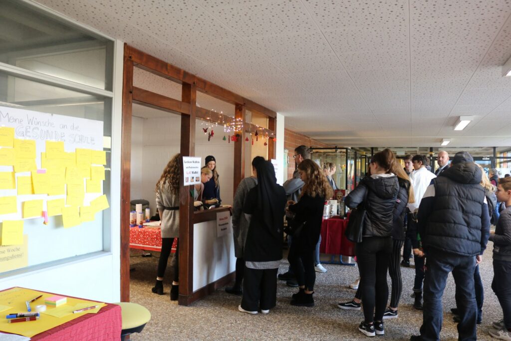 Schülerinnen und Schüler stehen an einem Informationsstand in der Schule.