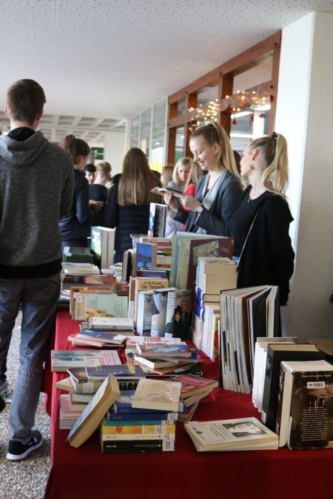 Schüler stehen an einem Tisch mit vielen Büchern in einem Flur.