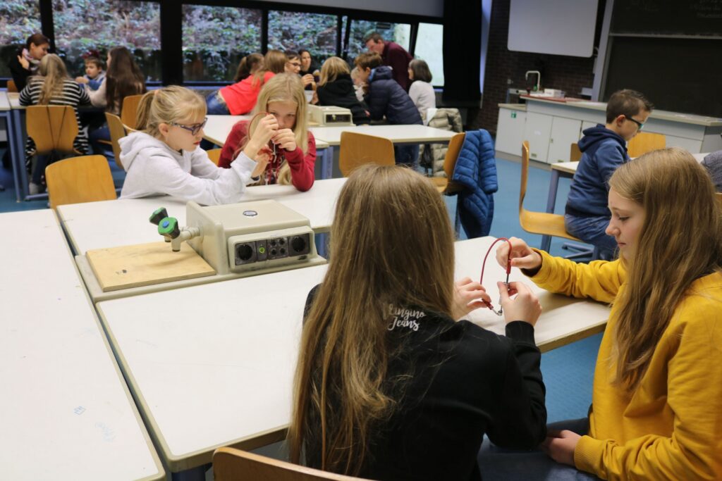Schülerinnen und Schüler führen Versuche an Tischen durch und arbeiten in Gruppen.