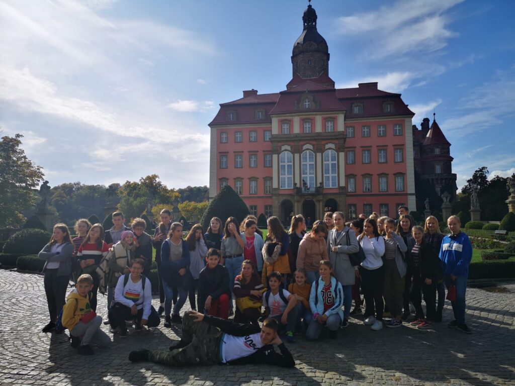 Gruppenzusammenkunft vor einem großen, historischen Gebäude im Freien.