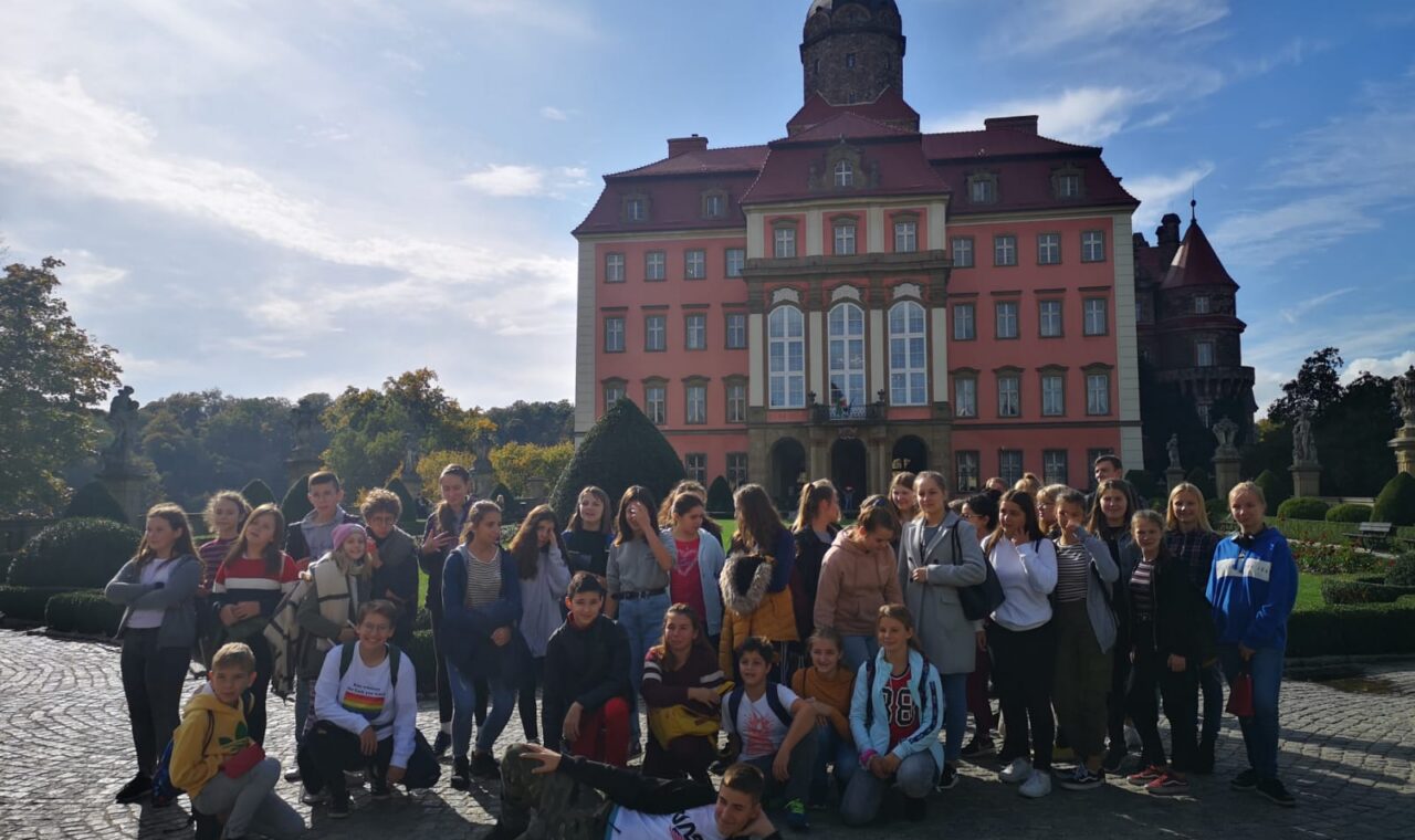 Gruppenzusammenkunft vor einem großen, historischen Gebäude im Freien.