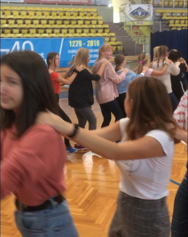 Schülerinnen tanzen in einer Reihe in einer Sporthalle.
