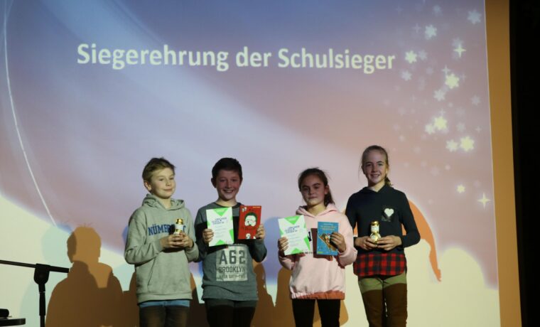 Siegerverleihung mit vier Kindern, die Pokale und Urkunden halten.