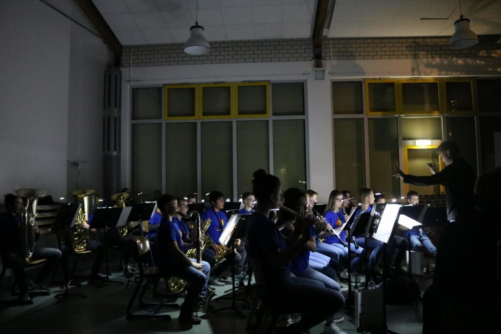 Schüler spielen in einem dunklen Raum Musik auf Blasinstrumenten.