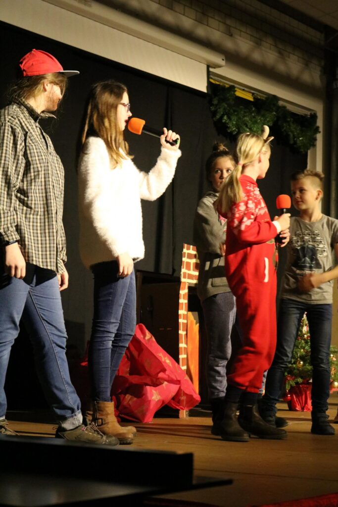 Schülerinnen und Schüler stehen auf der Bühne und sprechen ins Mikrofon.