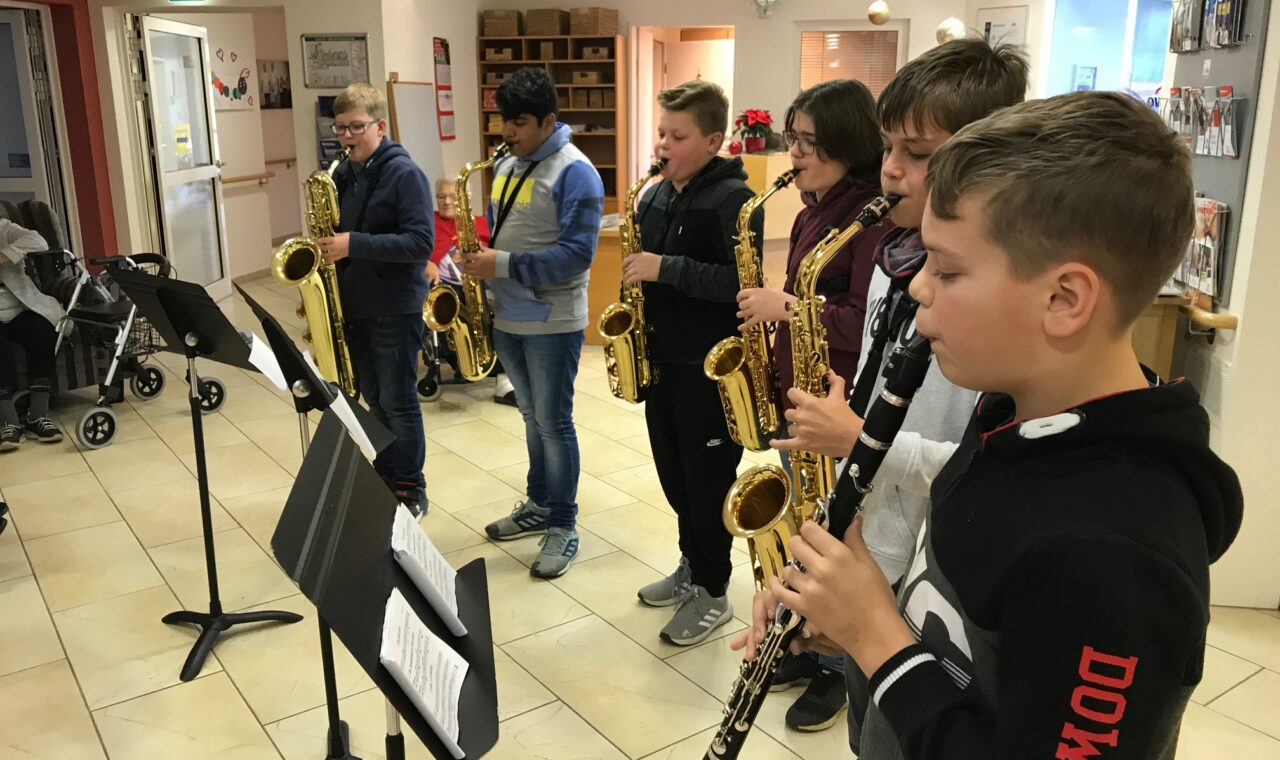 Sechs Schüler spielen in einer Reihe Saxophon und Klarinette.