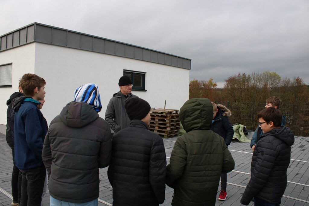 Gruppe von Schülern auf einem Dach mit einem Lehrer bei einer Besprechung.