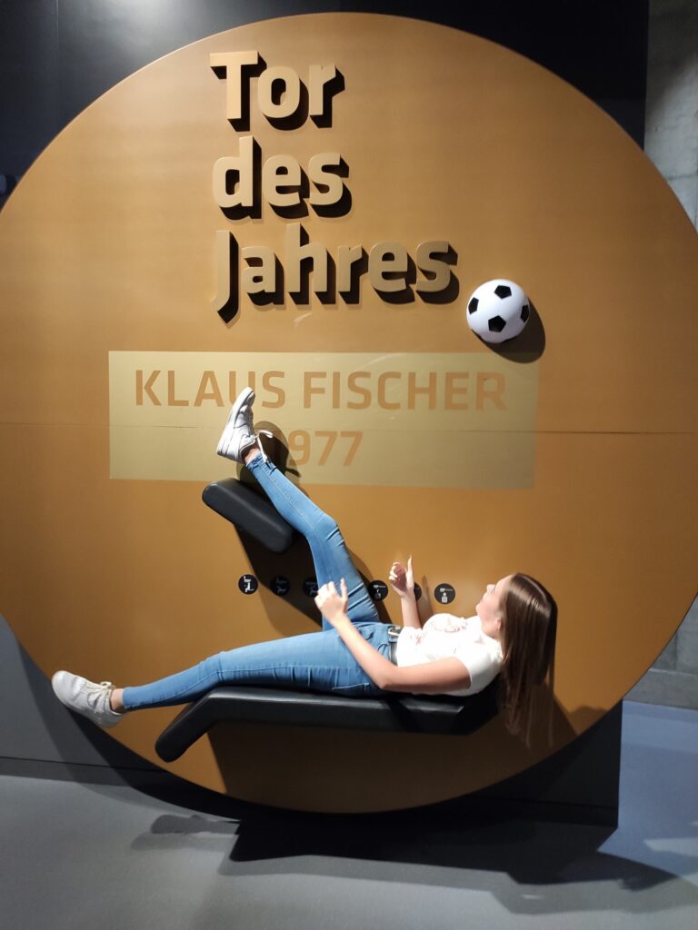 Eine Person liegt auf einem Stuhl und interagiert mit einem Fußball.