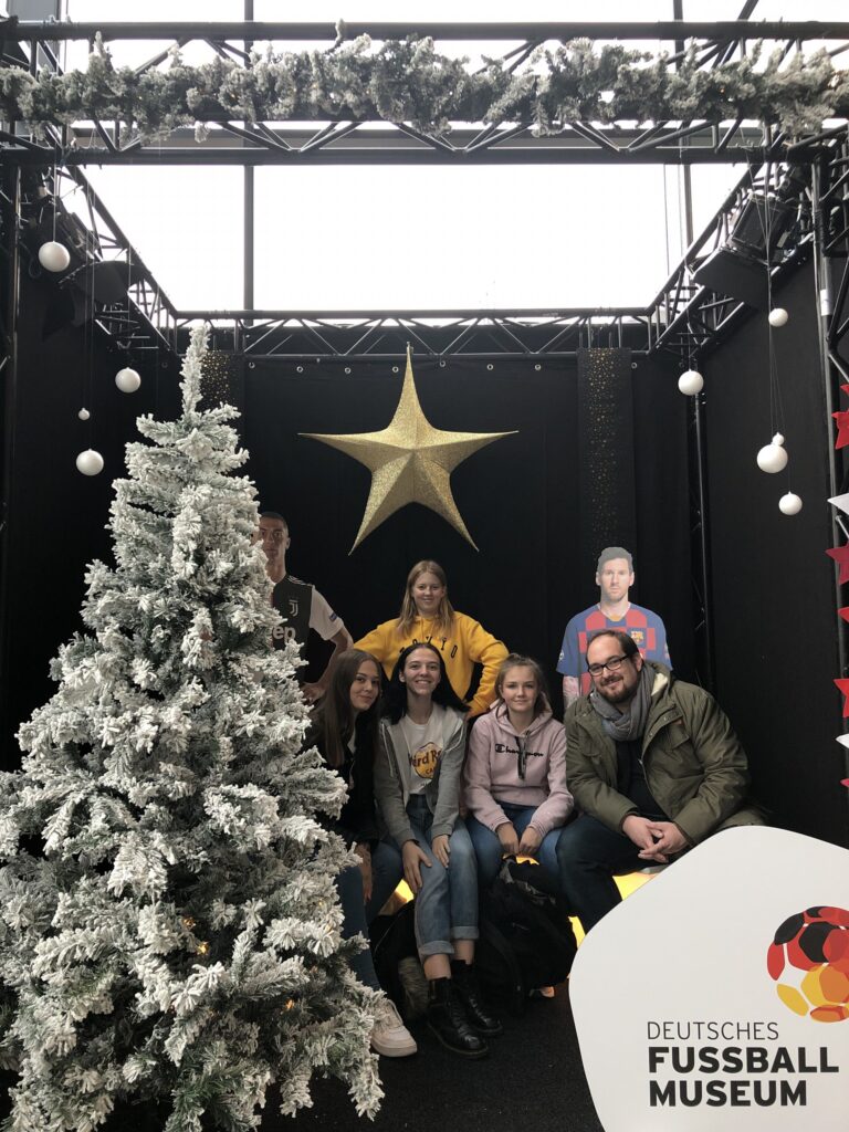 Gruppe von Personen posiert festlich vor einem Weihnachtsbaum und Stern.