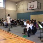 Schülerinnen und Schüler proben in einer Turnhalle mit Instrumenten.