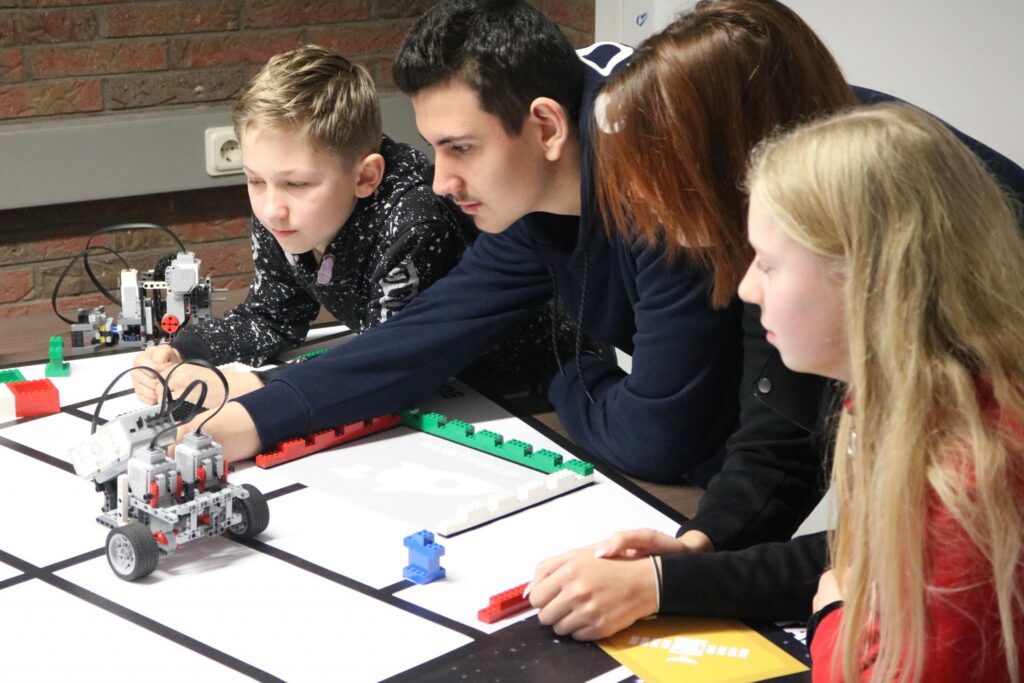Schüler arbeiten an einem Roboter-Projekt am Tisch.