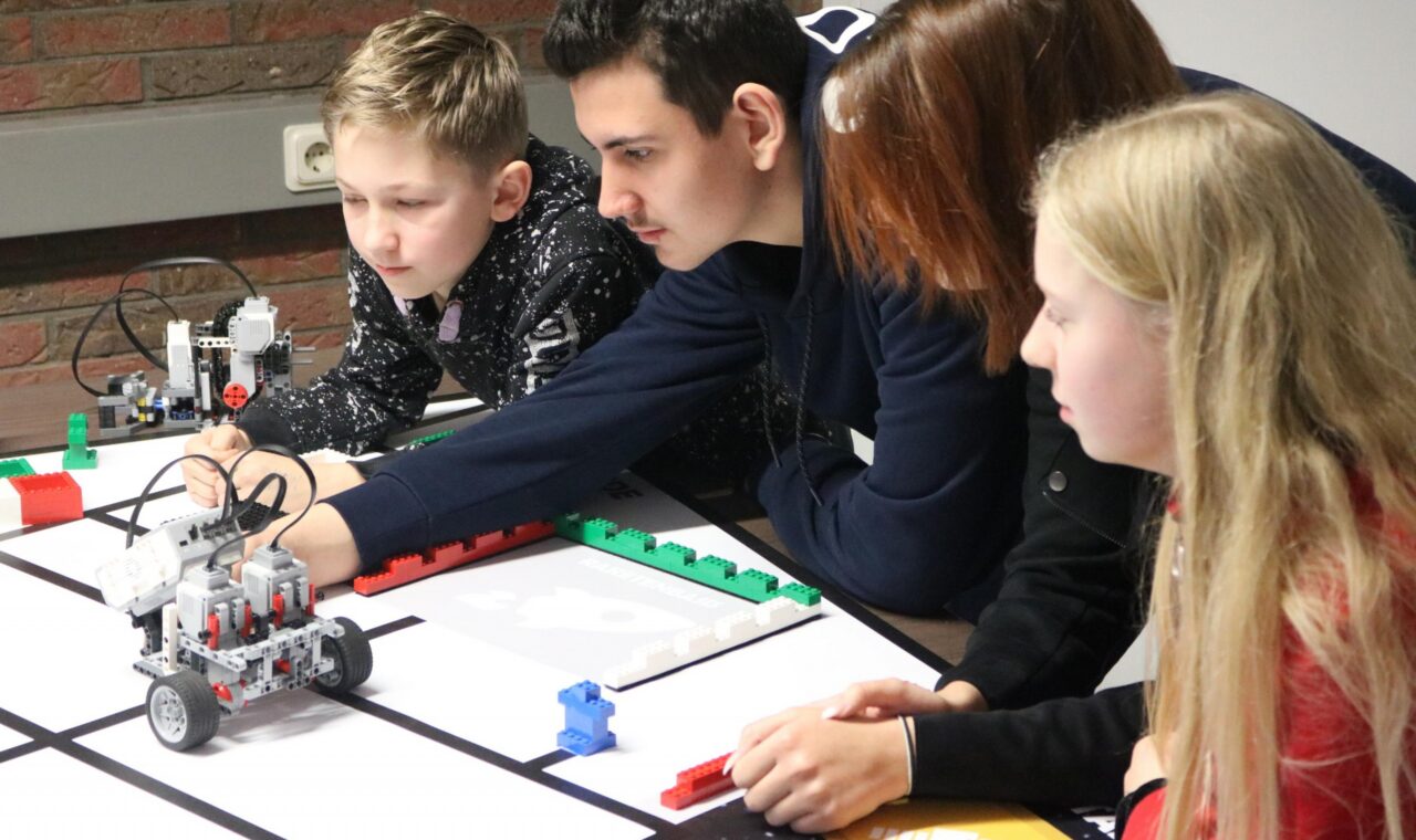 Schüler arbeiten an einem Roboter-Projekt am Tisch.