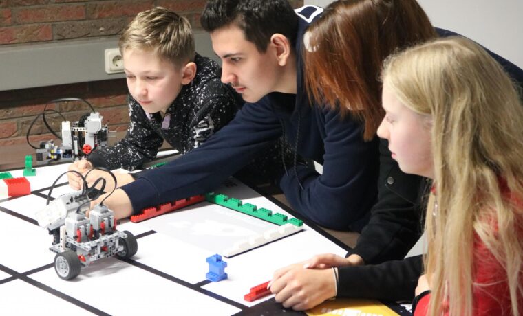Schüler arbeiten an einem Roboter-Projekt am Tisch.