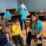 Kinder sitzen in einem Raum mit Musikinstrumenten und proben gemeinsam.