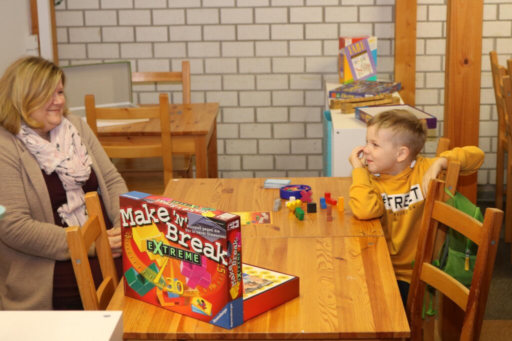 Eine Frau und ein Junge sitzen an einem Tisch mit einem Brettspiel.