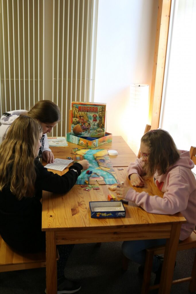 Drei Schülerinnen spielen ein Brettspiel an einem Tisch.