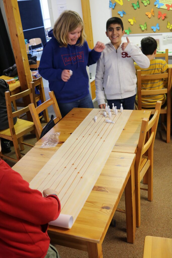 Schüler arbeiten an einem Tisch mit Holzbrett und Materialien.