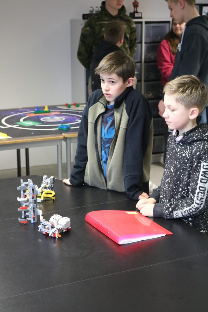 Zwei Jungen beobachten Modelle auf einem Tisch in einem Klassenraum.