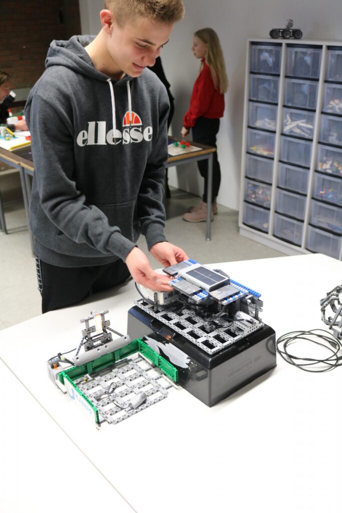 Ein Schüler arbeitet an einem technischen Gerät an einem Tisch.
