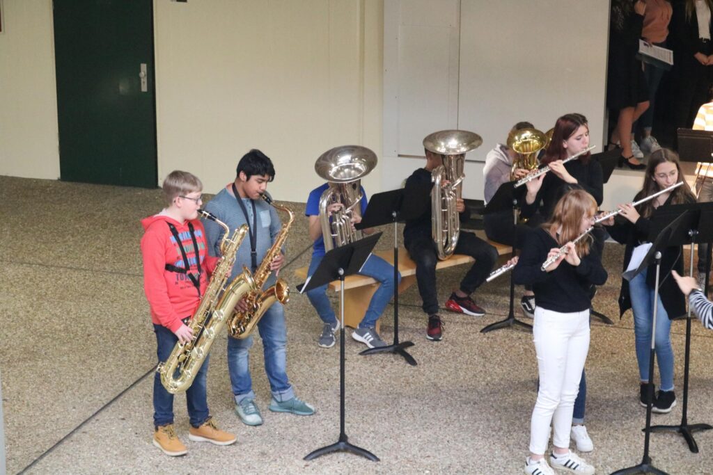 Schüler spielen verschiedene Blasinstrumente auf einer Bühne.