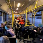 Schulklasse fährt mit dem Bus, Kinder sitzen und stehen im Innenraum.