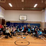 Schüler spielen Musikinstrumente in einer Turnhalle.