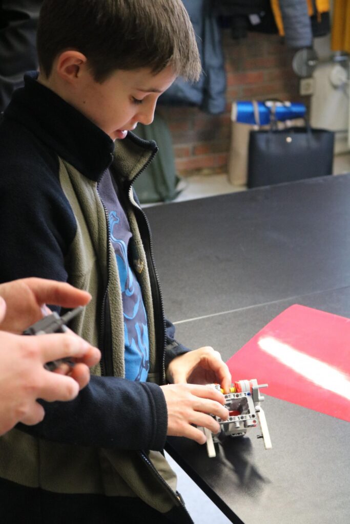 Ein Junge baut an einem kleinen Roboter auf einem Tisch.